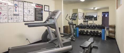 A gym with treadmills, dumbbells, and exercise posters on the wall.