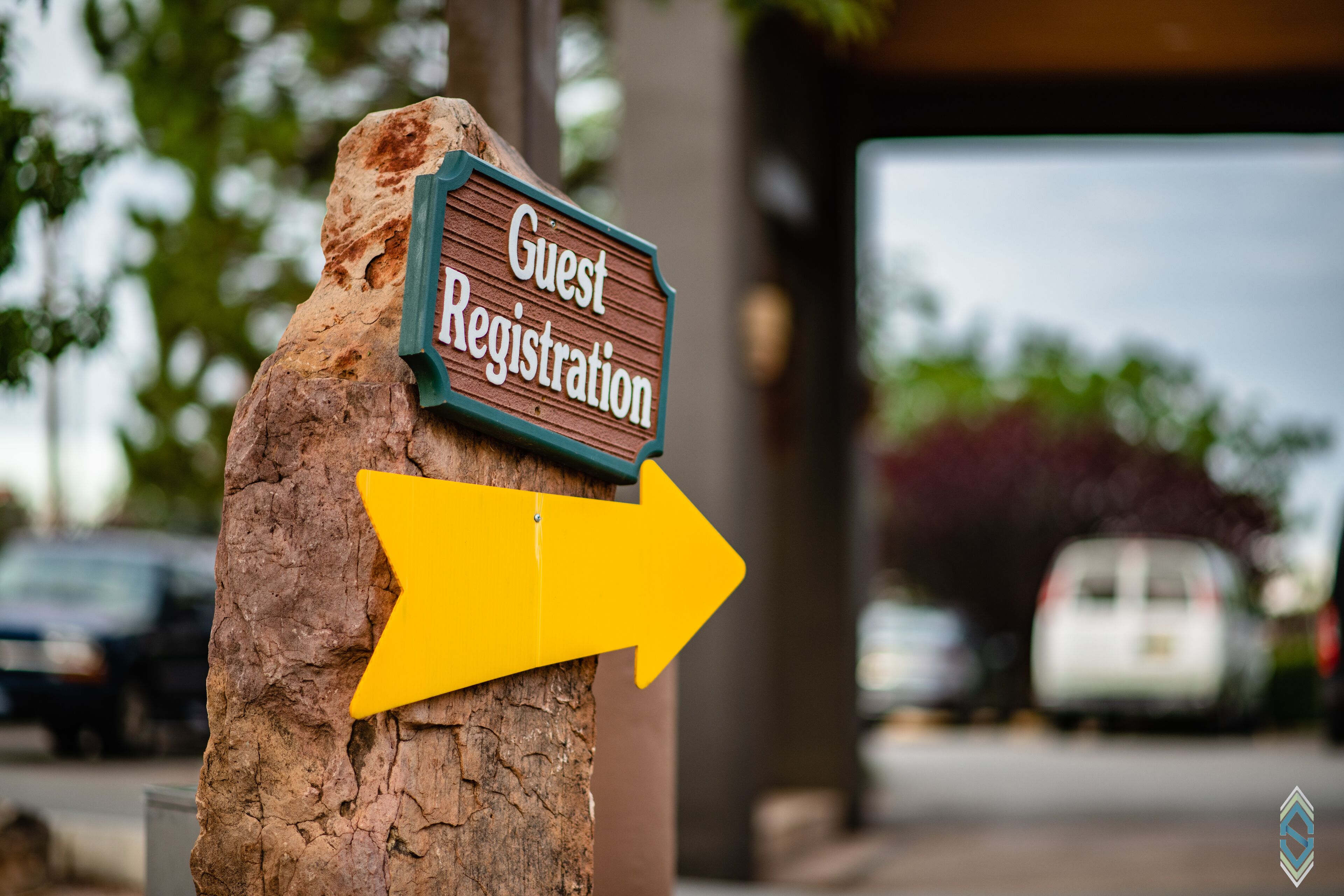 A wooden sign with "Guest Registration" and a yellow arrow pointing right.