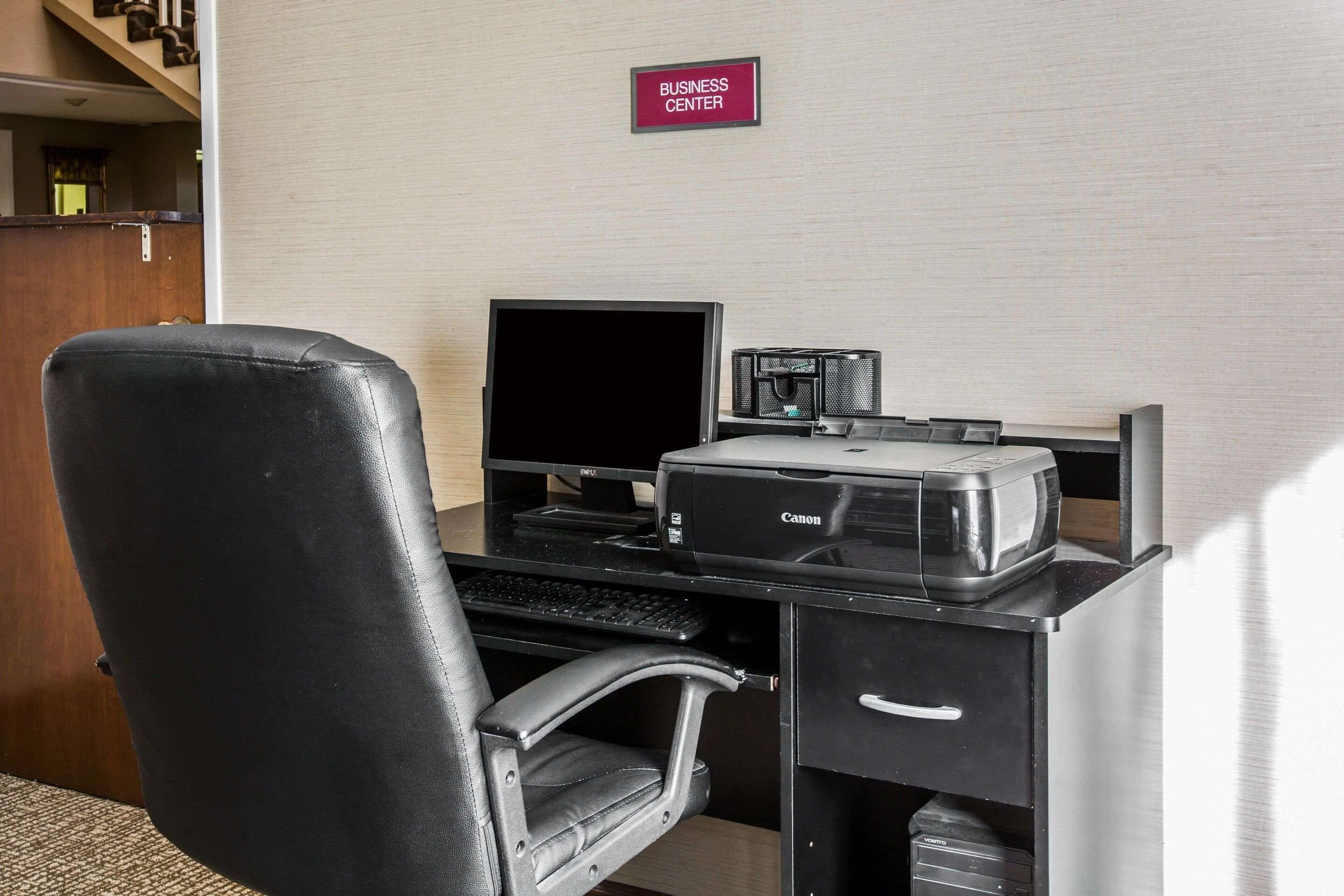 A business center desk with a computer, printer, and chair.