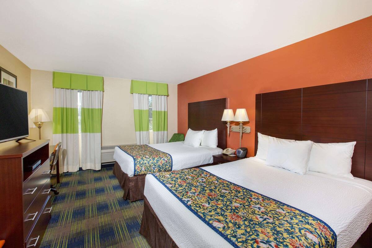 A hotel room with two beds, a TV, a desk, and a chair.