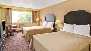 Une chambre d’hôtel avec deux lits, un bureau, une télévision et une fenêtre avec des rideaux.