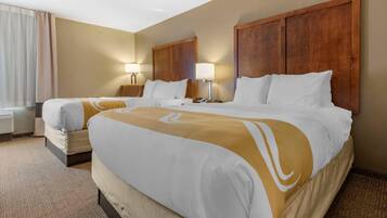 A hotel room with two beds, a large window with curtains, a wooden headboard, and bedside lamps.