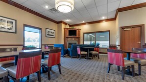 A hotel lobby with a fireplace, dining area, and a large window.