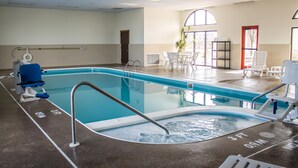 An indoor swimming pool with a clear lane, a changing room with a blue chair, and a sunlit area with chairs and a plant.