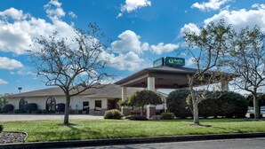 A hotel with a covered entrance, a parking lot, and a clear sky.