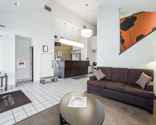 A modern hotel room with a sofa, a coffee table, a kitchen area, and a large painting on the wall. - Sleep Inn South Jordan - Sandy (South Jordan)