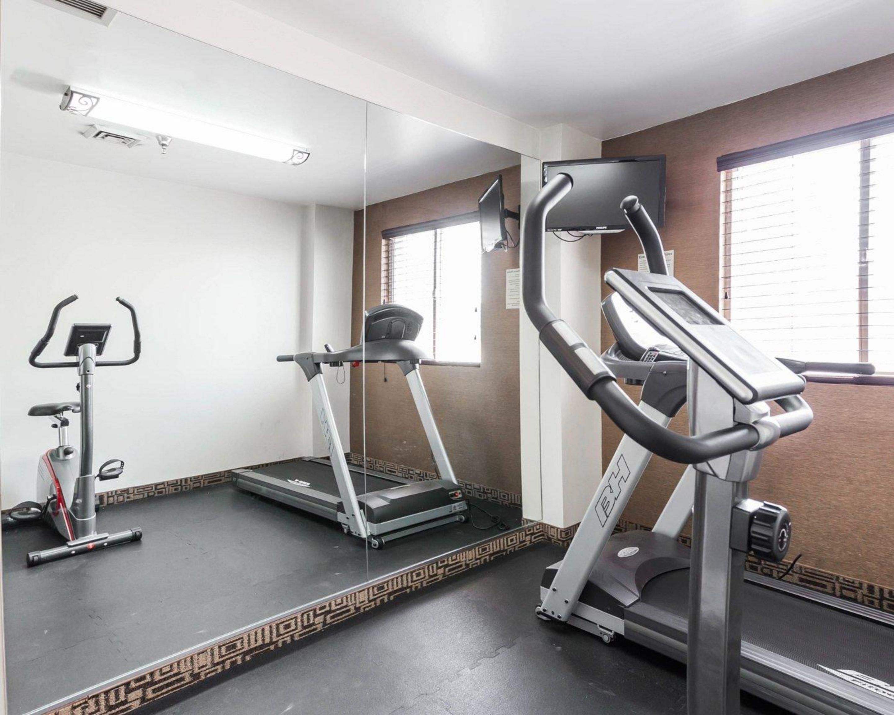 Un gimnasio con cinta de correr, elíptica y bicicleta estática.