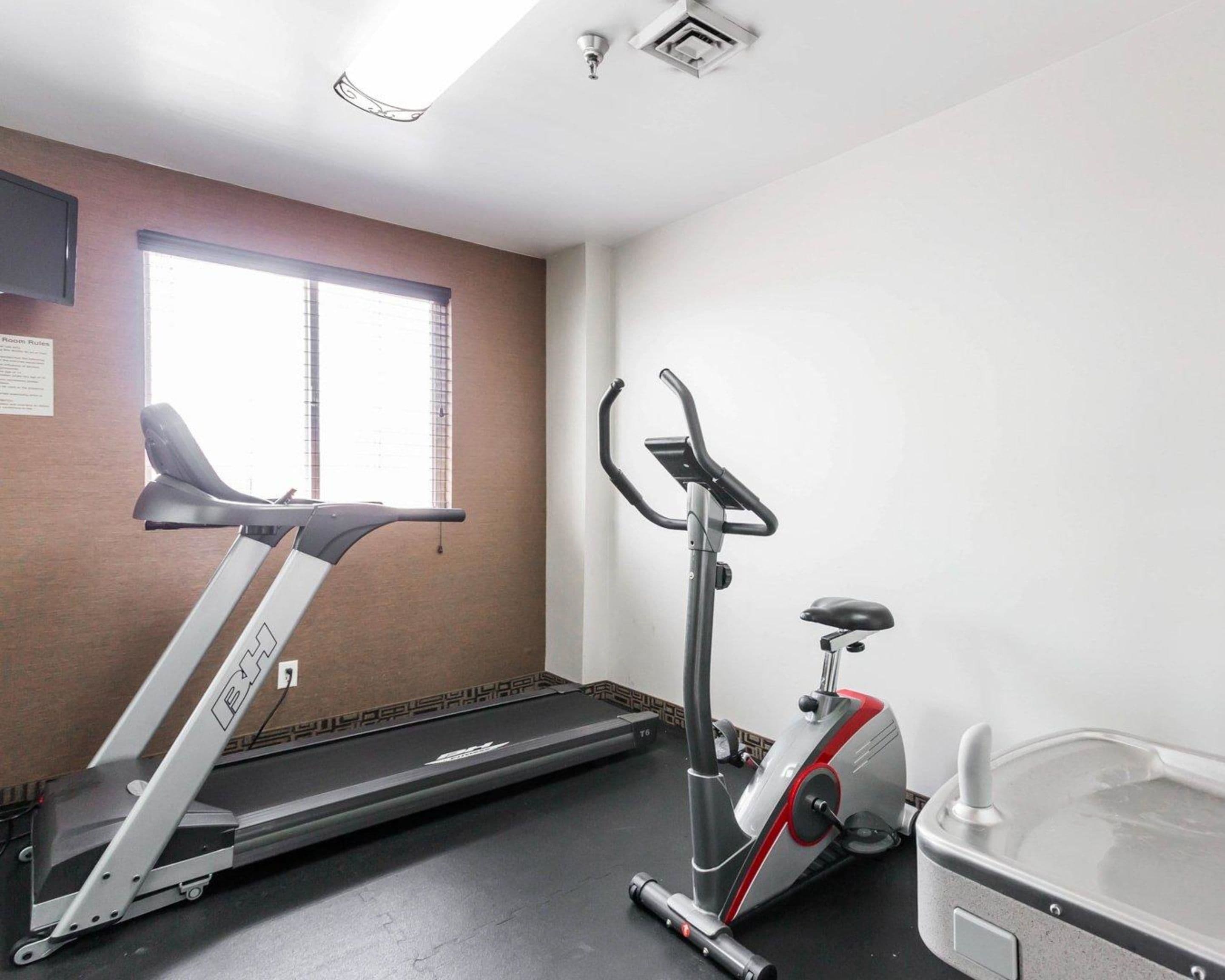 Un gimnasio con una caminadora, una máquina elíptica y una bicicleta estática.