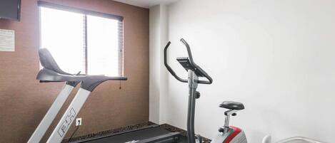 Un gimnasio con una caminadora, una máquina elíptica y una bicicleta estática.