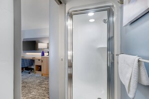 A modern bathroom with a glass shower door, a white towel hanging on a rack, and a visible sink area. - Sleep Inn South Jordan - Sandy (South Jordan)