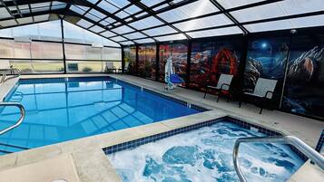 A covered swimming pool with a hot tub, lounge chairs, and a mural on the wall.