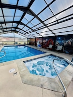 Una piscina cubierta con hidromasaje, sillones de descanso y un mural en la pared.