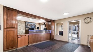 A reception area with wooden cabinets, a reception desk, a stone wall, and a clock on the wall. - Best Western Empire Towers (Sioux Falls)