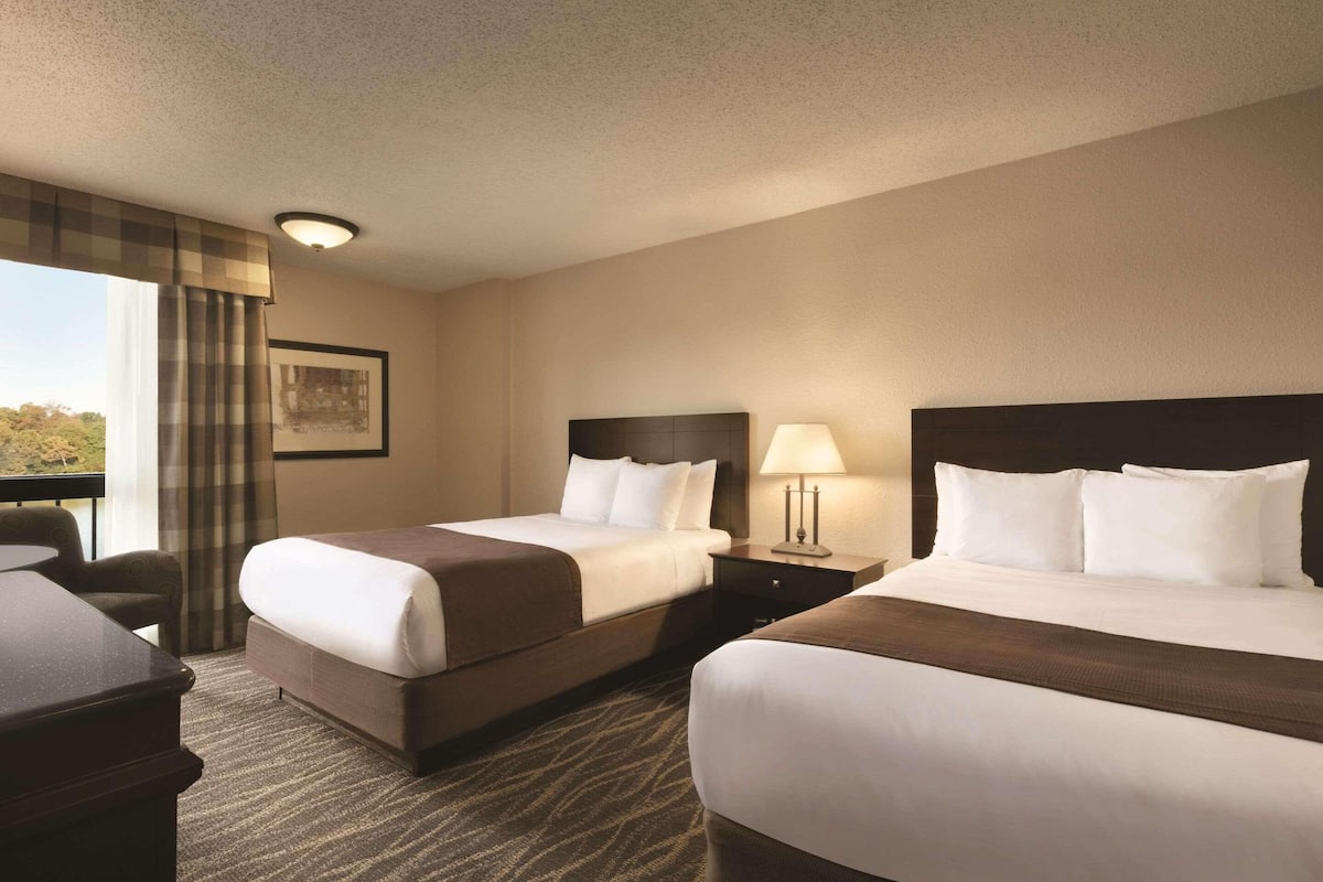 Ein Hotelzimmer mit zwei Betten, einem Schreibtisch und einem Stuhl.