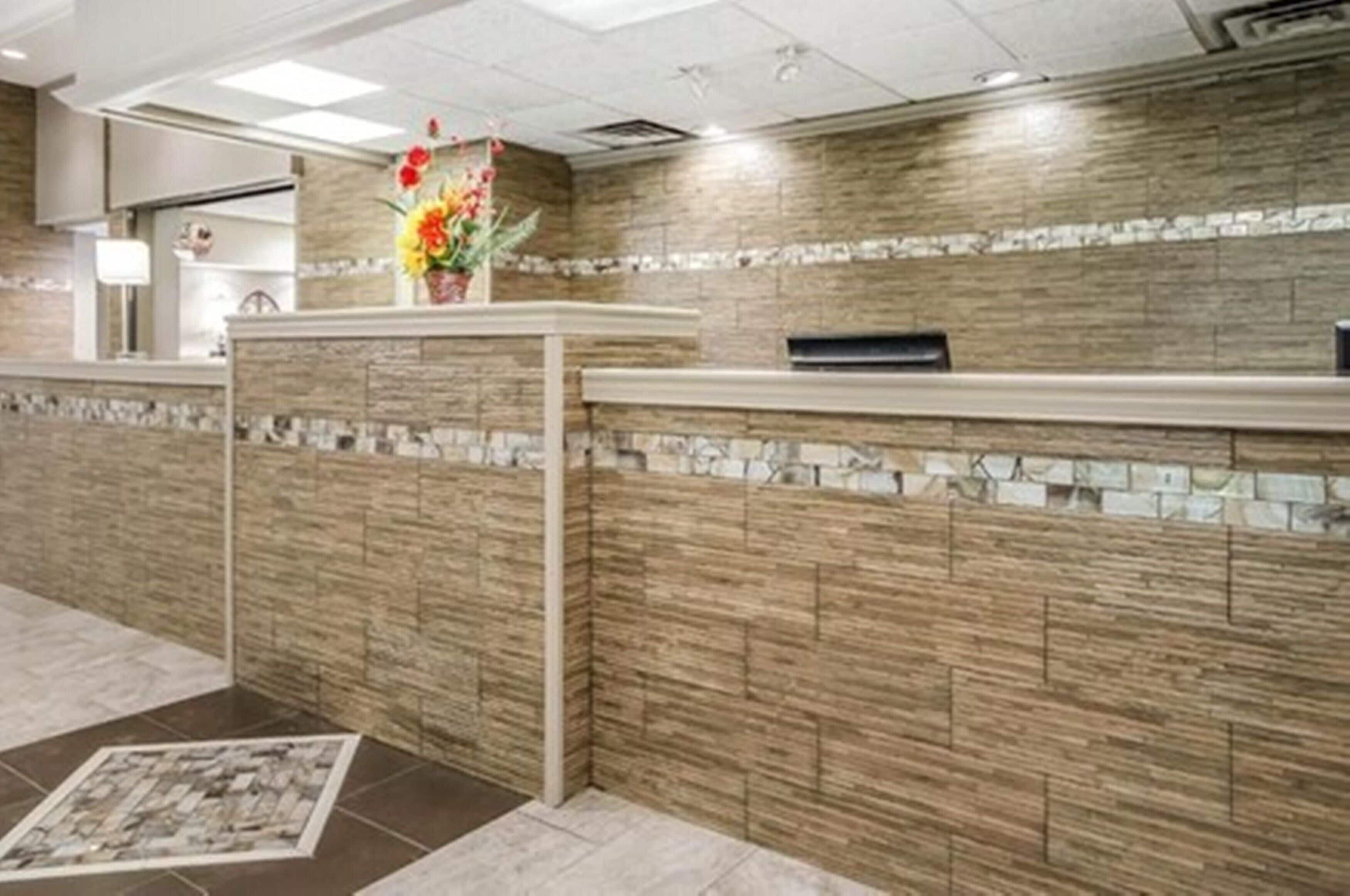 A reception area with a stone wall, a reception desk, and a vase with flowers.