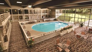 An indoor pool area with a large window view, multiple seating areas, and a patterned floor. - Radisson Hotel Louisville North (Clarksville)