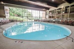 Una piscina interior con vistas despejadas al exterior gracias a grandes ventanales, rodeada de sillones de descanso y una zona de estar cubierta.