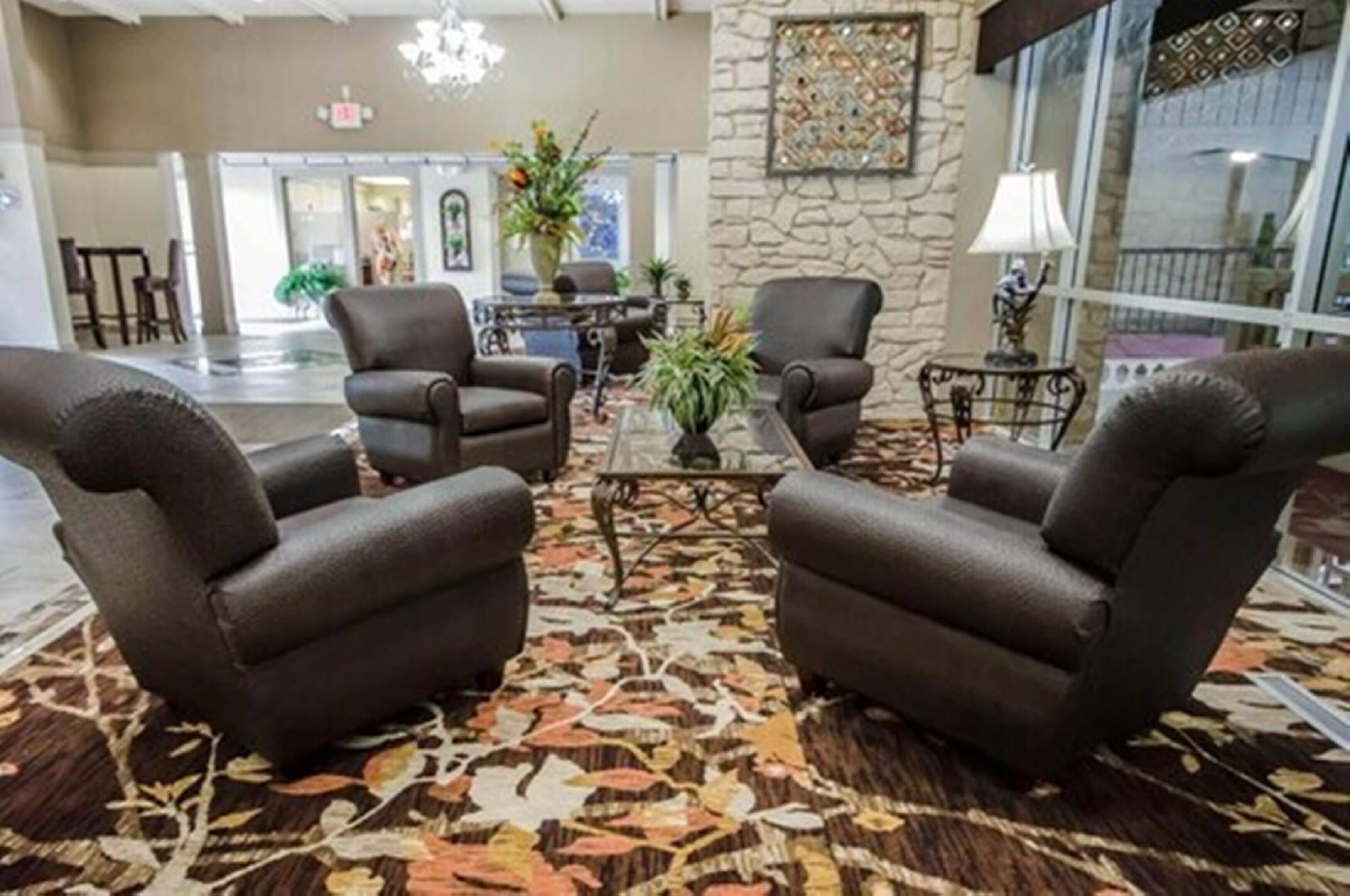 A lobby with leather armchairs, a coffee table, and a patterned carpet.
