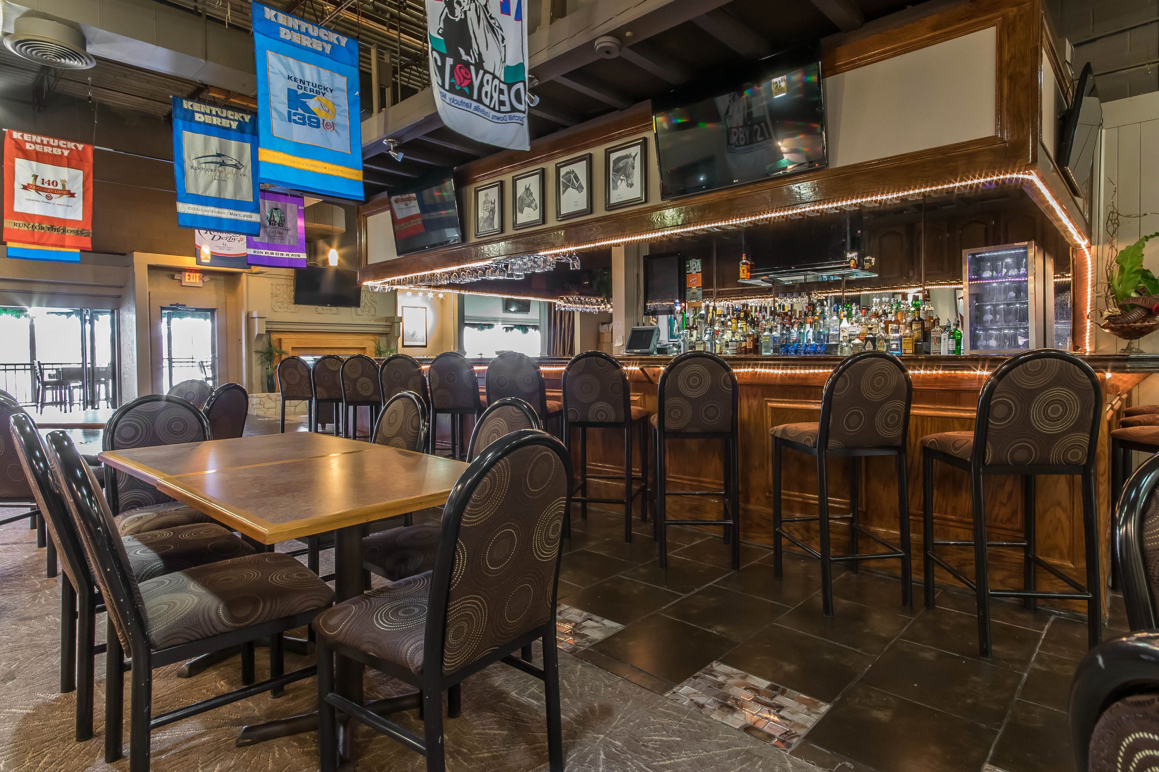 Un restaurante con zona de bar, varias mesas y sillas, y banderines colgantes.