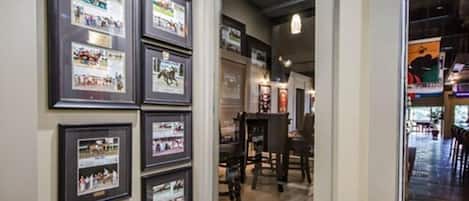 Una galería de fotos enmarcadas en una pared, una mesa de madera con sillas y vista hacia un comedor.