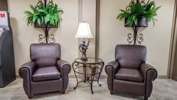 Two leather armchairs, a small table with a lamp, and two potted plants on metal stands.