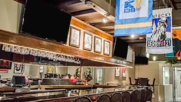 A bar area with a counter, bar stools, and framed pictures on the wall.