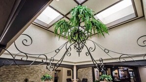 A lobby with a high ceiling, a chandelier, and a view through the skylight. - Radisson Hotel Louisville North (Clarksville)