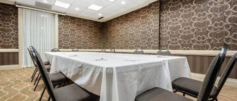 A conference room with a large table, chairs, and a patterned wall.
