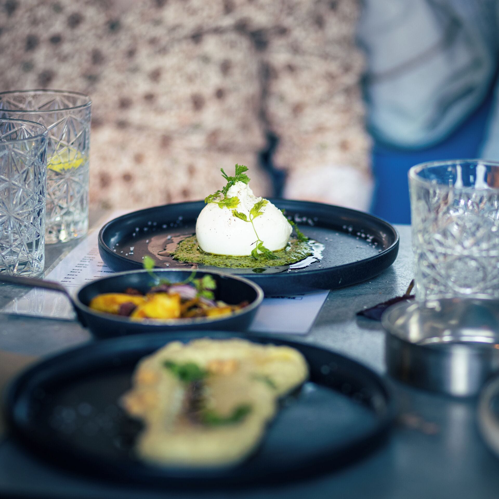A dining table with a plate of food, a glass of water, and a menu.