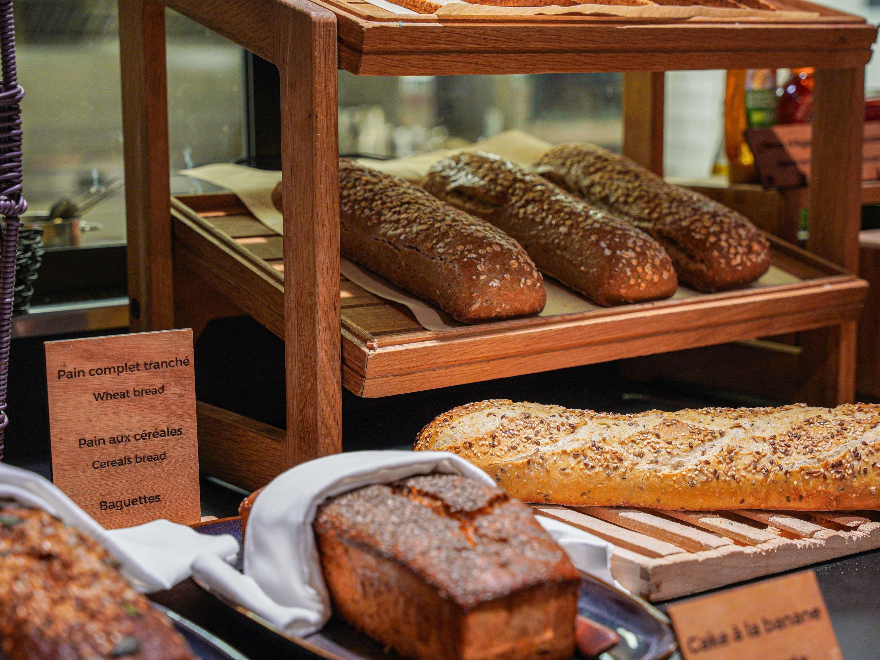 Une vitrine de boulangerie présentant différents types de pain, notamment du pain de blé et des pains aux céréales.