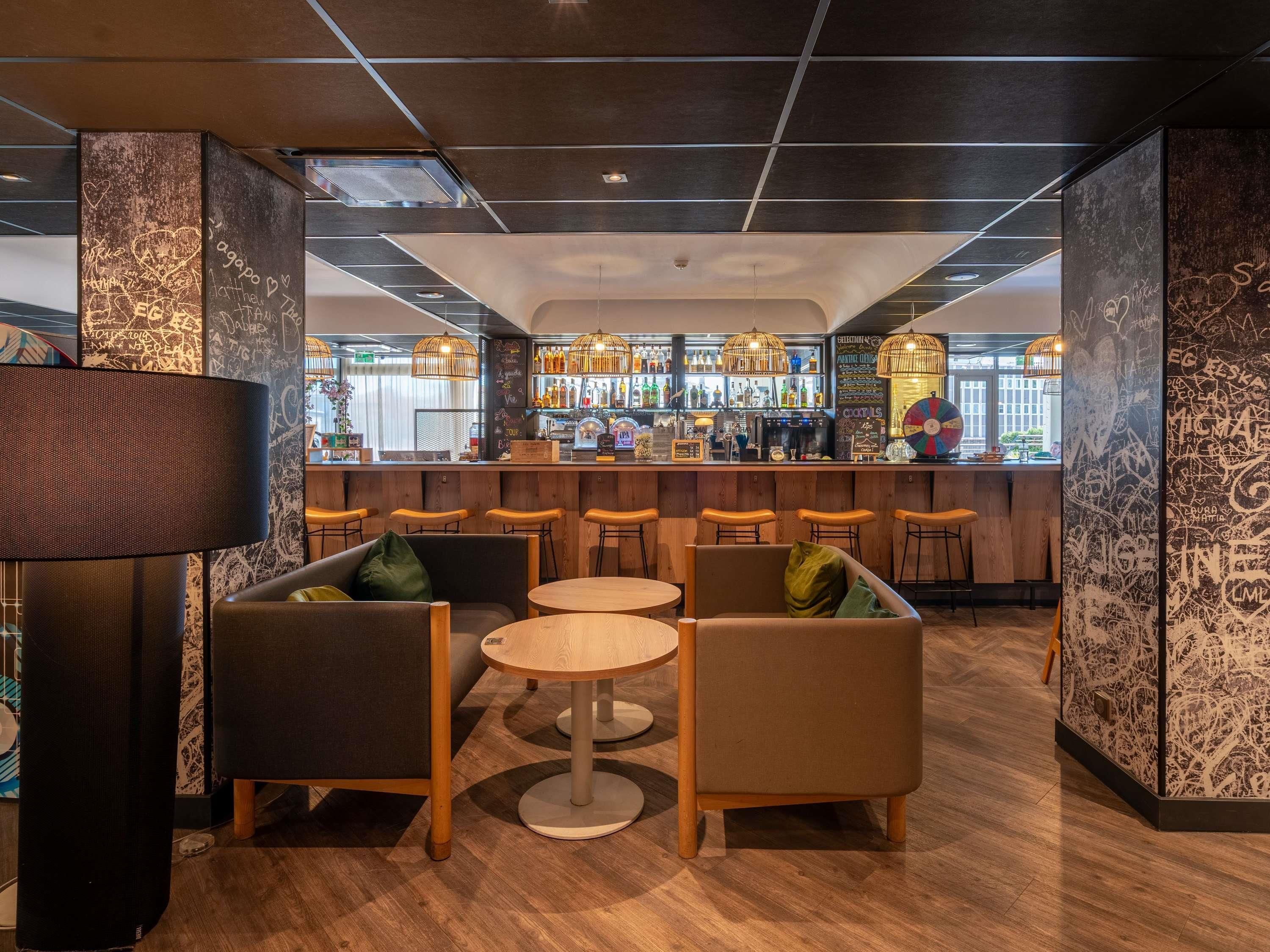 A bar area with wooden furniture, a bar counter with bottles, and a ceiling with exposed beams.