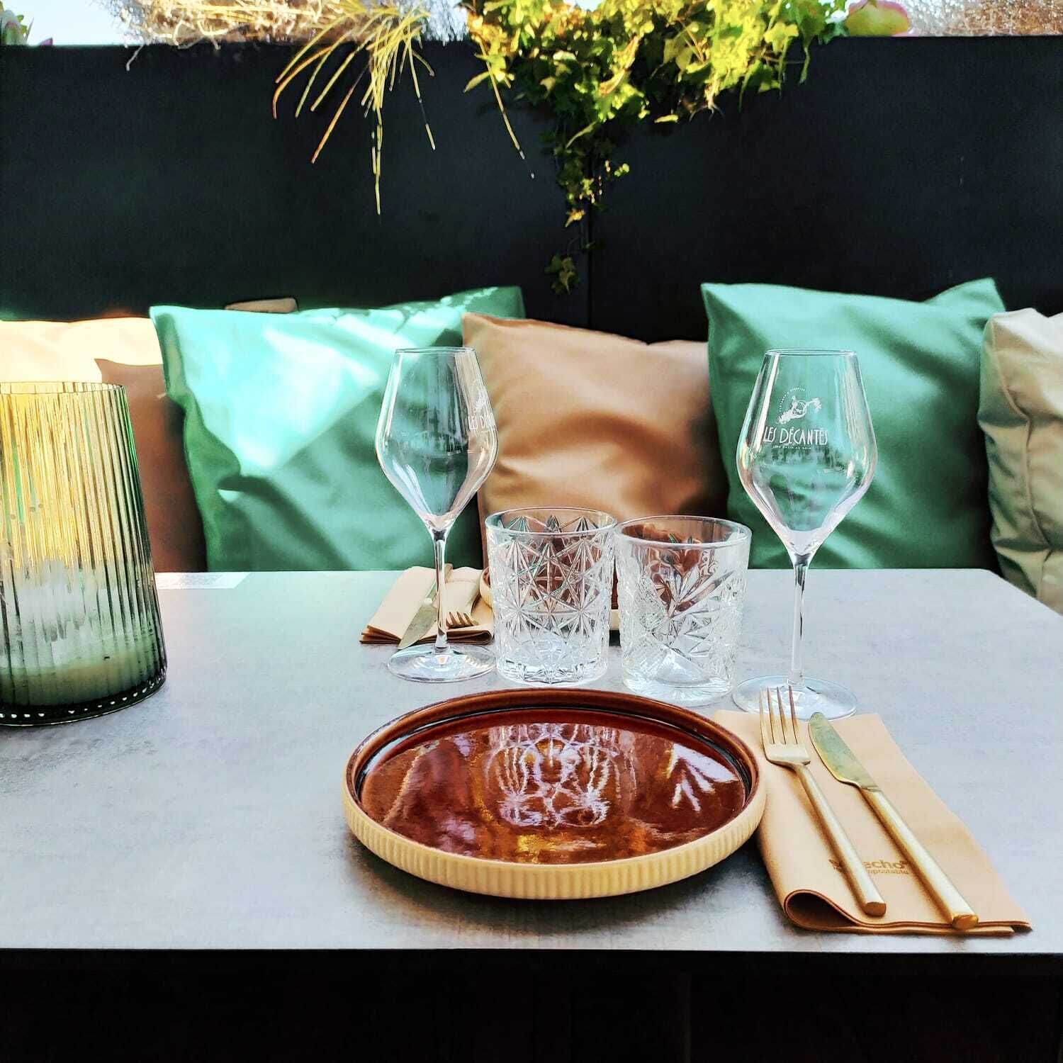 A table set for a meal with a plate of food, two wine glasses, and three crystal glasses.