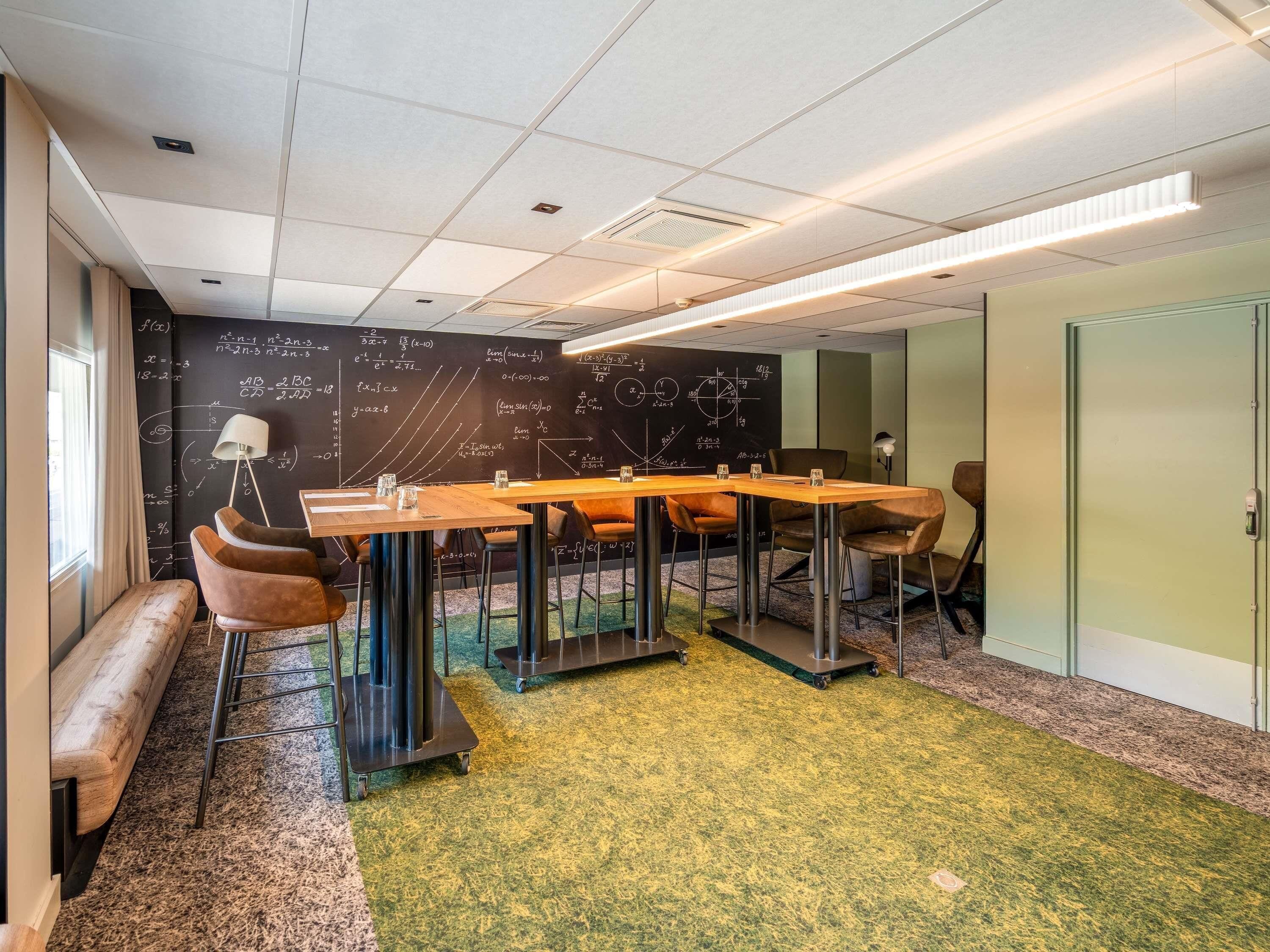 A conference room with a large table, chairs, a blackboard with mathematical equations, and a carpeted floor.