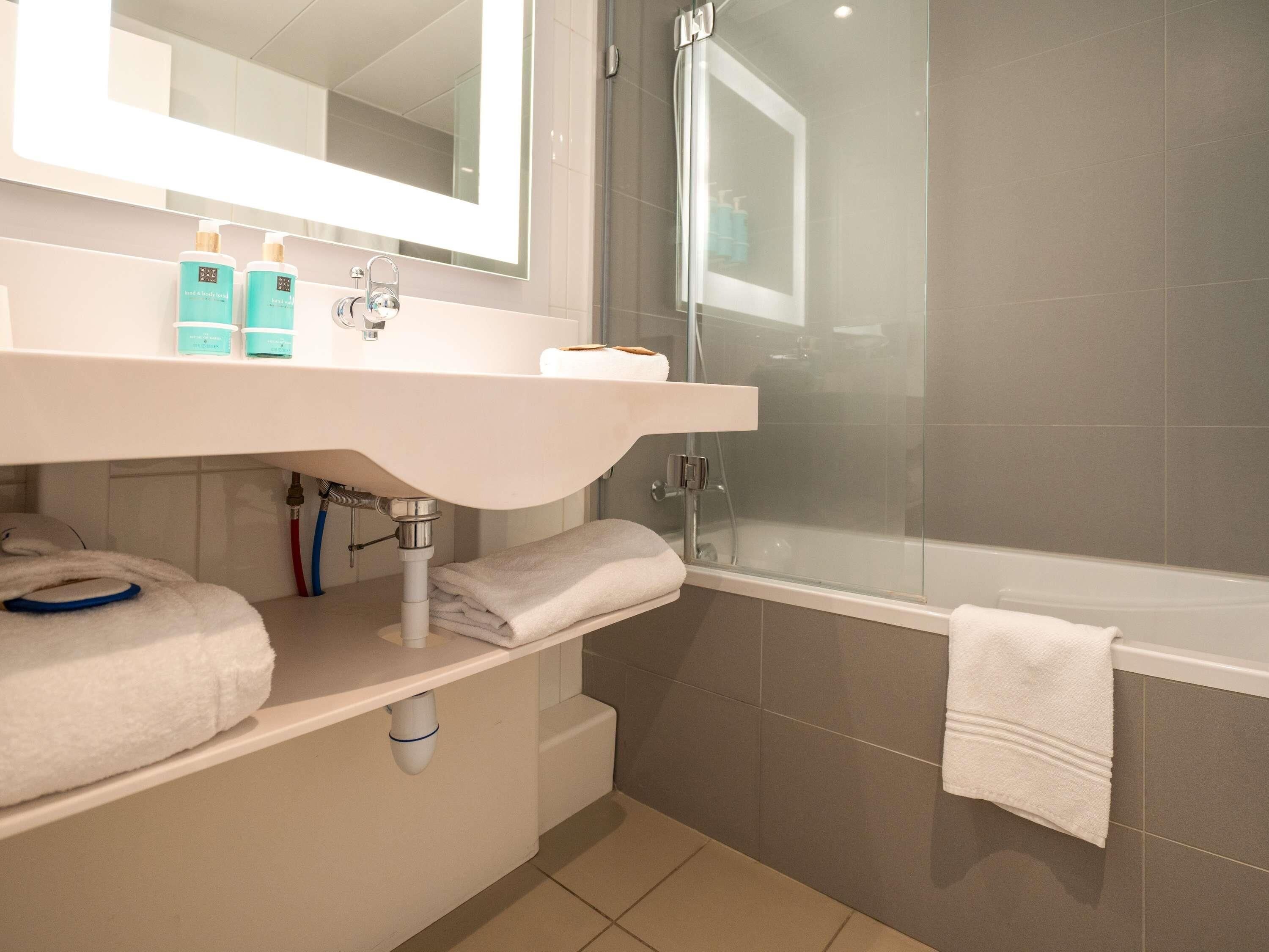 Ein modernes Badezimmer mit Waschbecken, Spiegel und Duschkabine aus Glas.