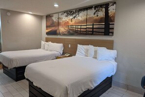 Two single beds with white bedding, a wooden headboard, and a large landscape painting above.