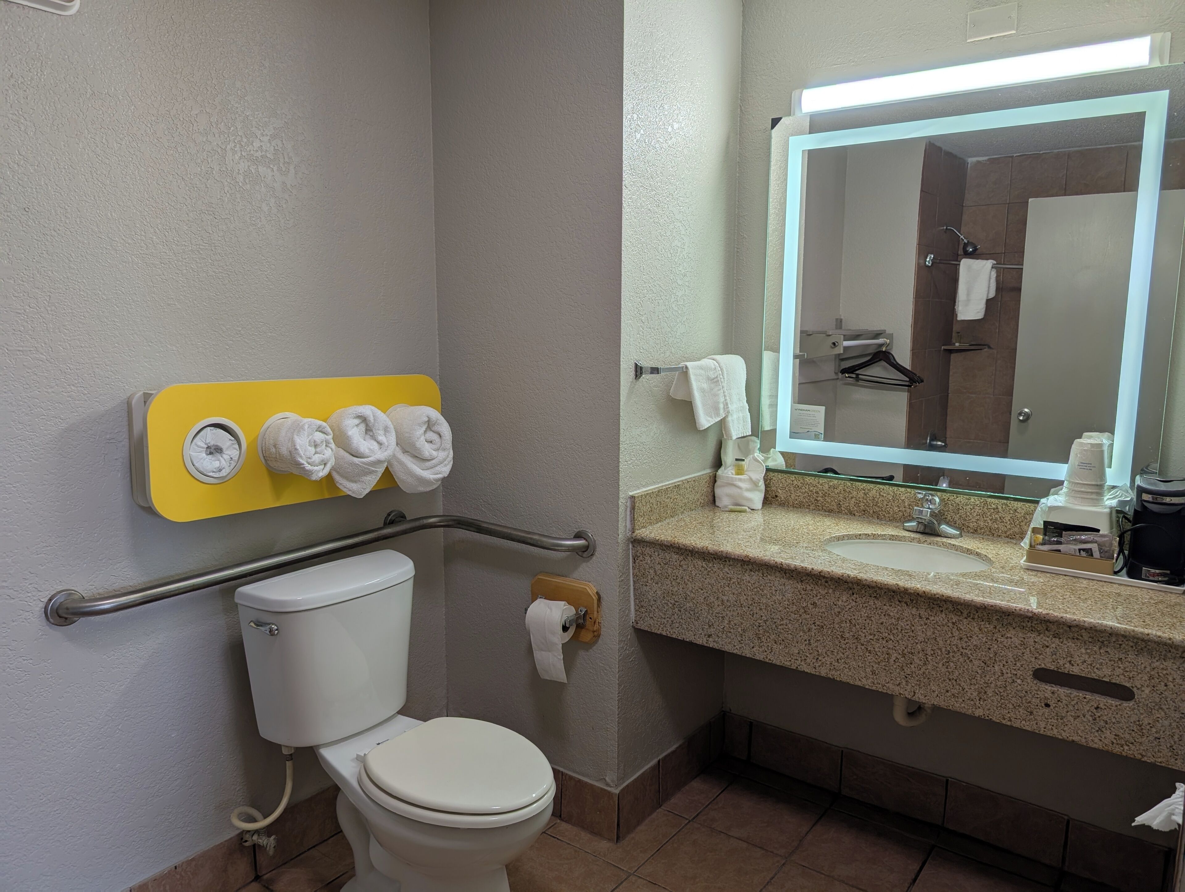 A bathroom with a toilet, a sink with a mirror, and a towel rack with towels.