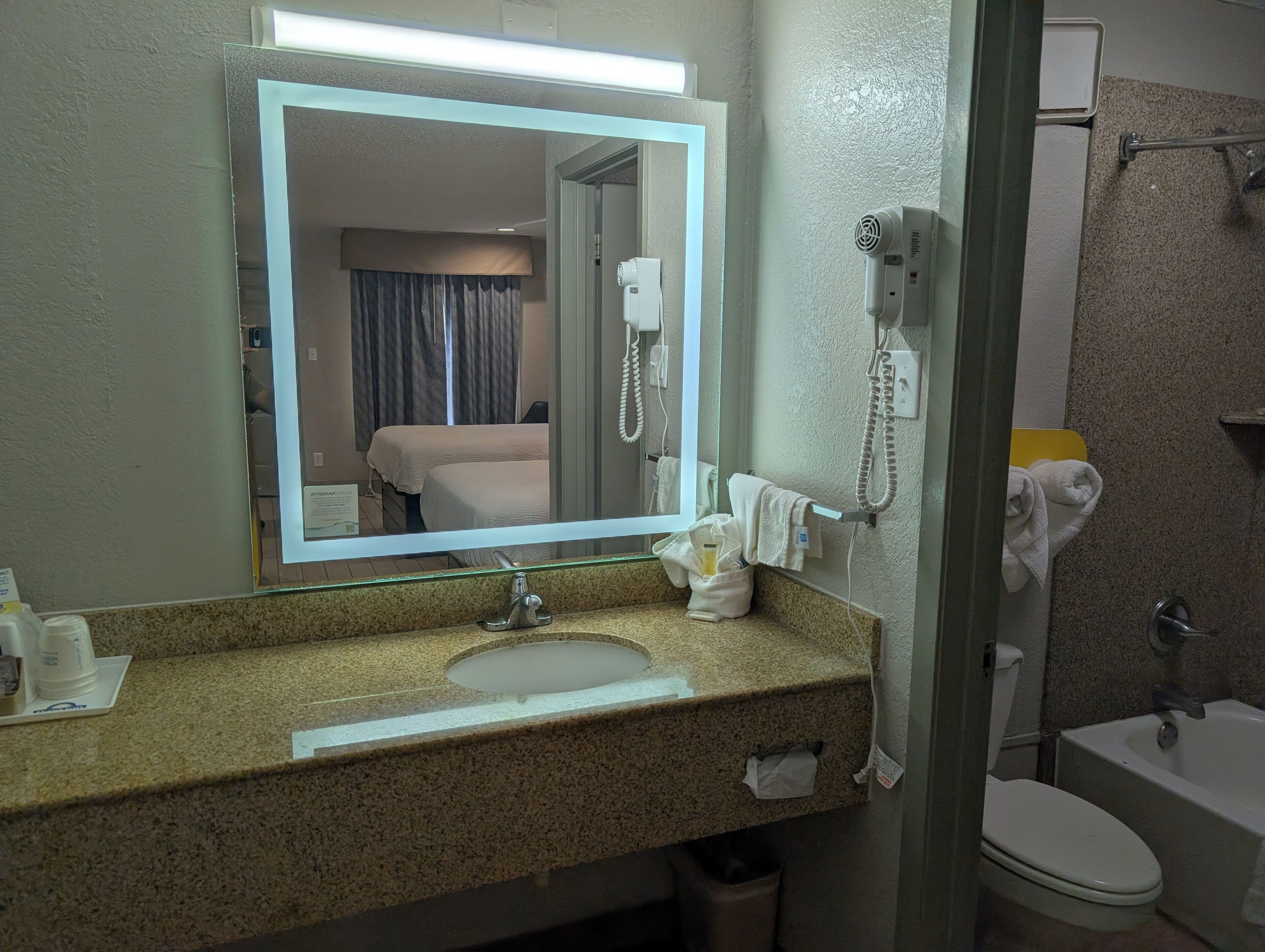 A bathroom with a sink, mirror, and a telephone.