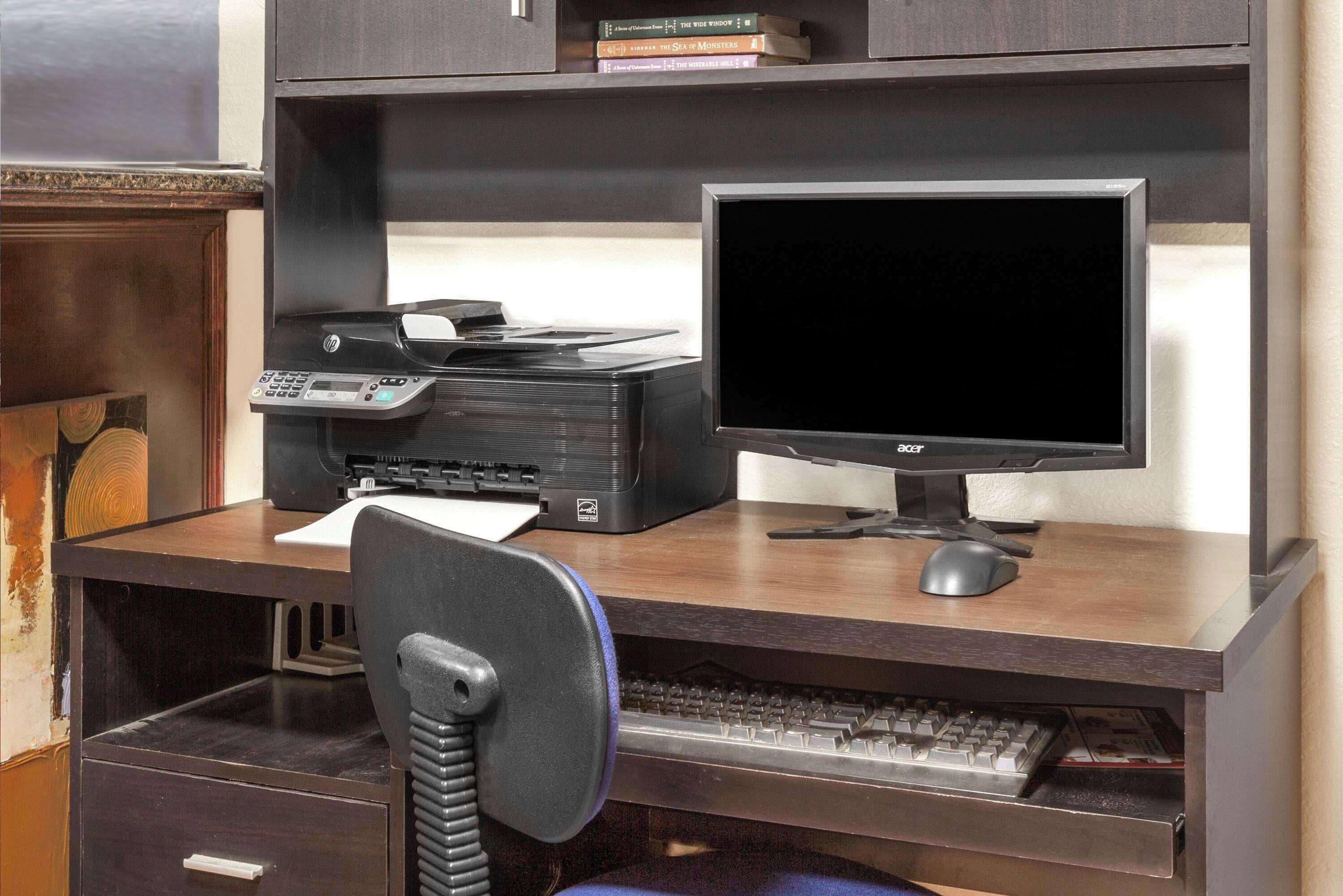A wooden desk with a desktop computer, keyboard, and monitor.