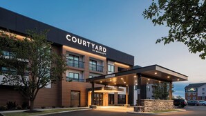 L’entrée d’un hôtel Courtyard by Marriott, avec un espace extérieur abrité, une signalisation claire et un parking.