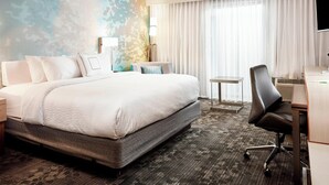 Une chambre d’hôtel avec un grand lit, un bureau avec une chaise, une petite table et un téléviseur.