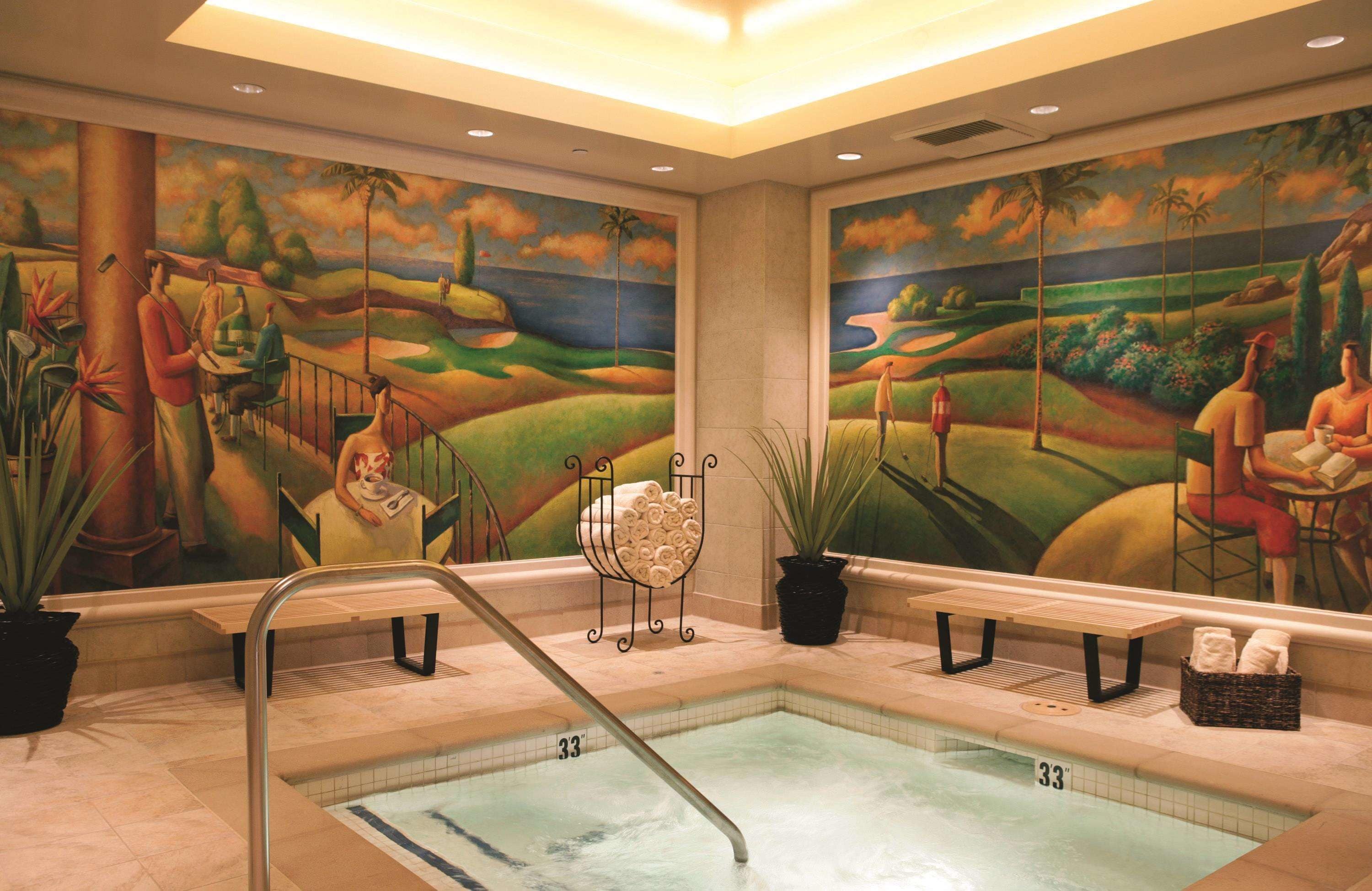 Zona de piscina con un mural, una banca y un perchero para toallas.