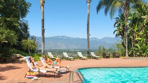 Un espace aménagé au bord de la piscine, avec des chaises longues et une vue sur les montagnes.