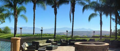 An outdoor seating area with stone flooring, a fire pit, and a view of mountains.