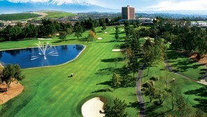 Un terrain de golf avec un étang, des arbres et un bâtiment en arrière-plan.