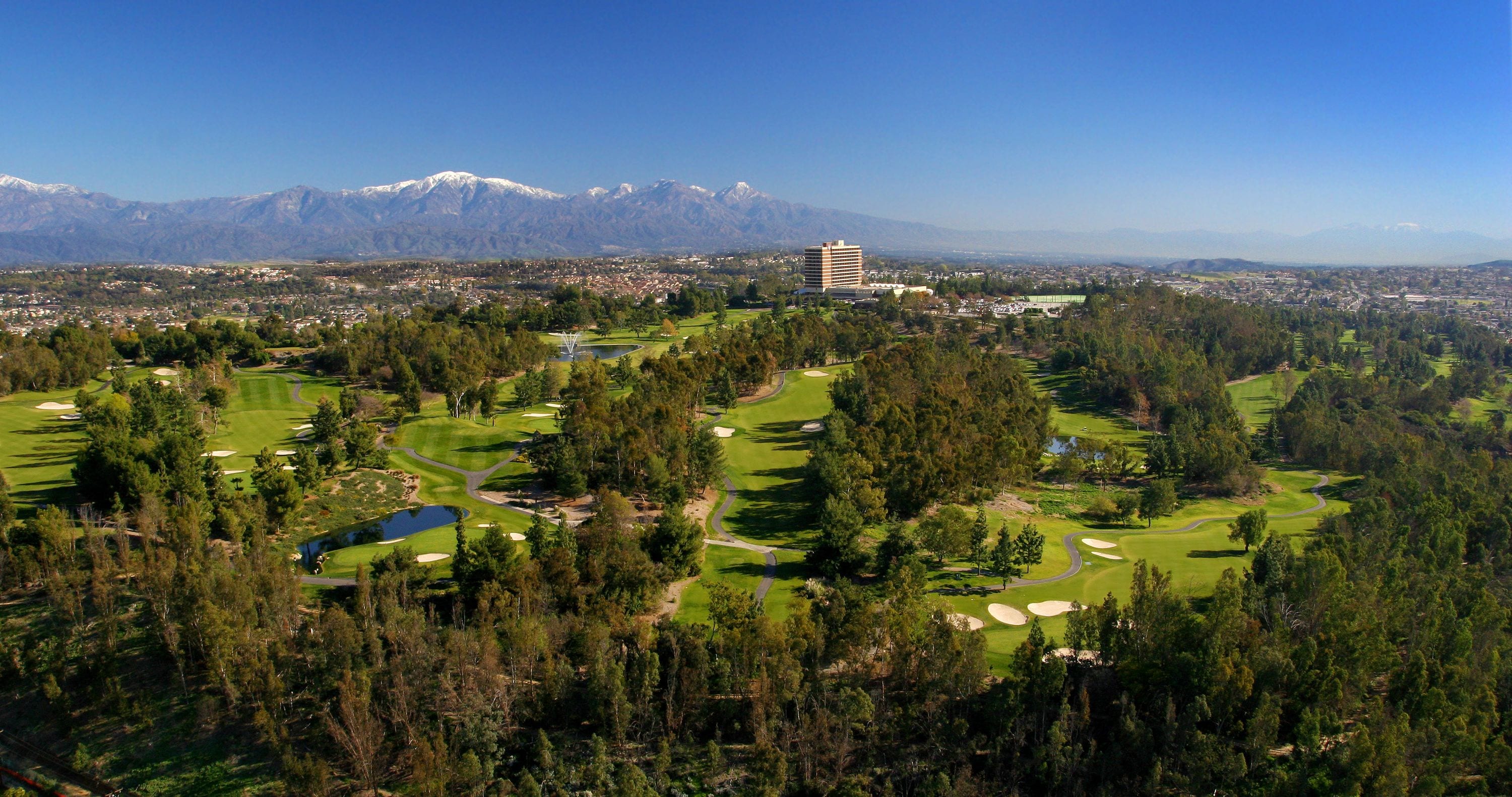 A golf course with a view of mountains and a cityscape in the background.