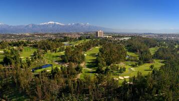 A golf course with a view of mountains and a cityscape in the background.