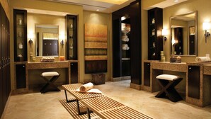 Une salle de bain moderne avec deux lavabos, des bancs et un grand miroir.