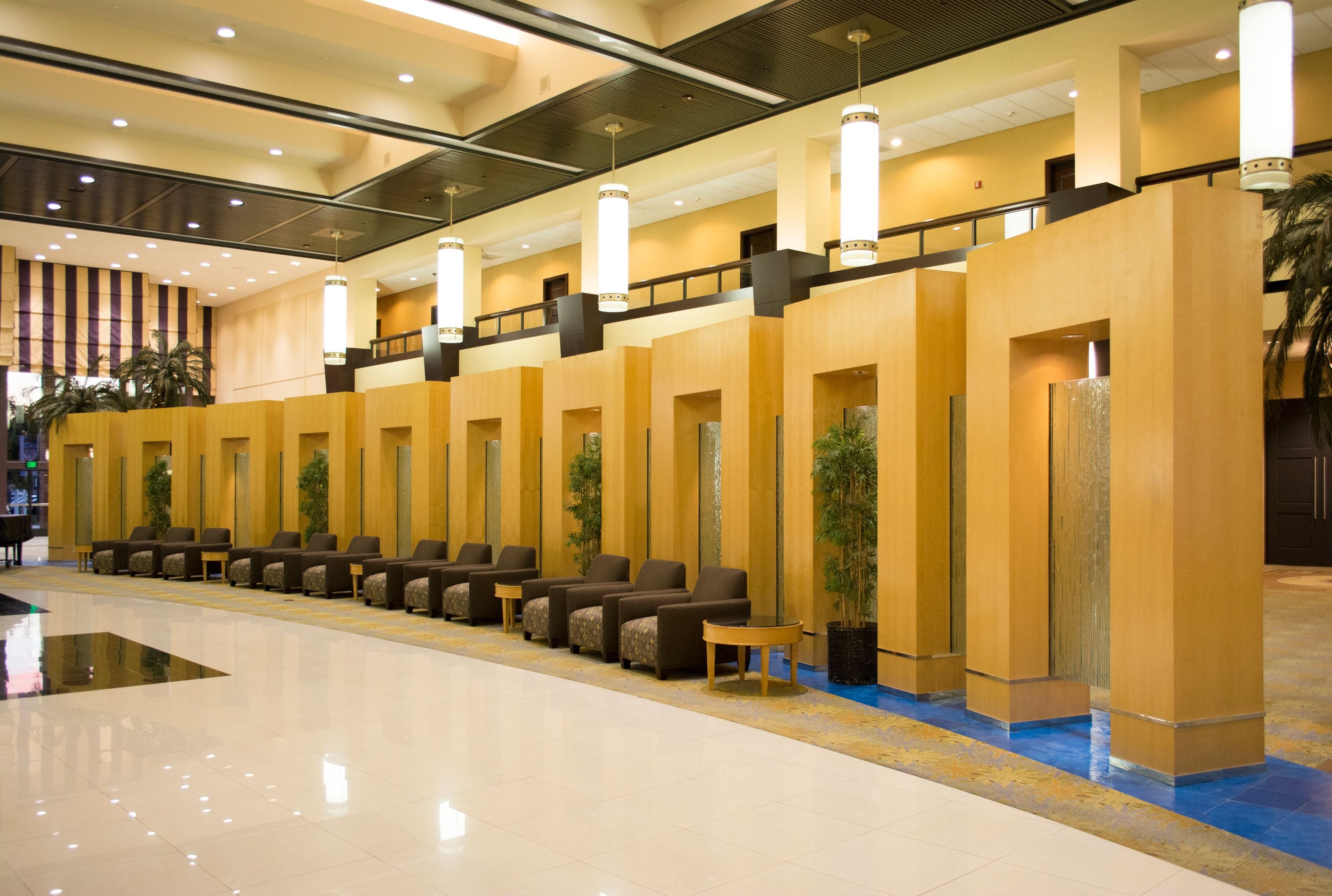 Un vestíbulo de hotel con una fila de zonas de estar, un suelo pulido y un diseño moderno de techo.
