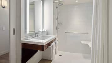 A modern bathroom with a walk-in shower, a large mirror, and a vanity with a sink.
