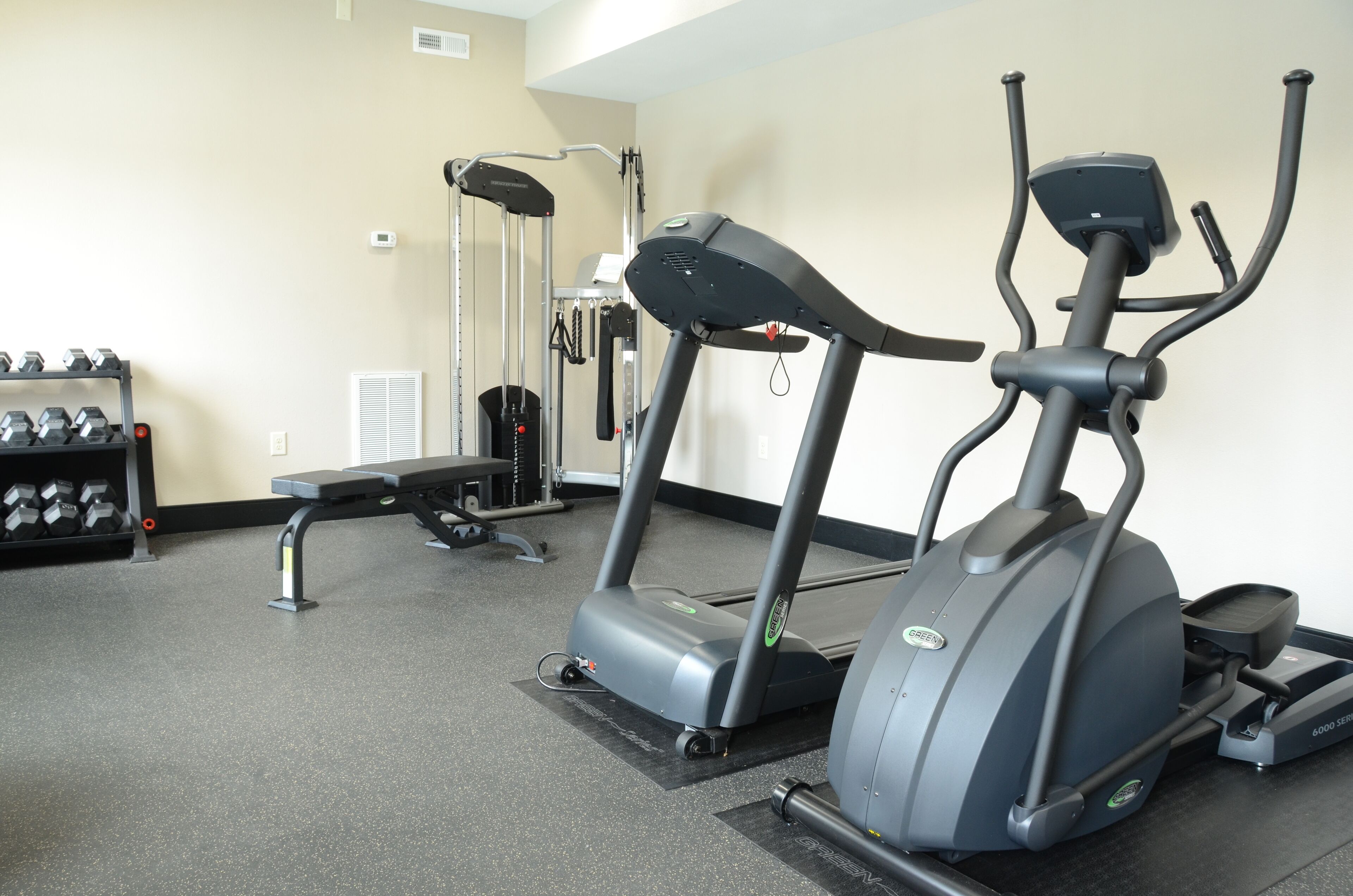 A gym with treadmills, dumbbells, and a weight machine.
